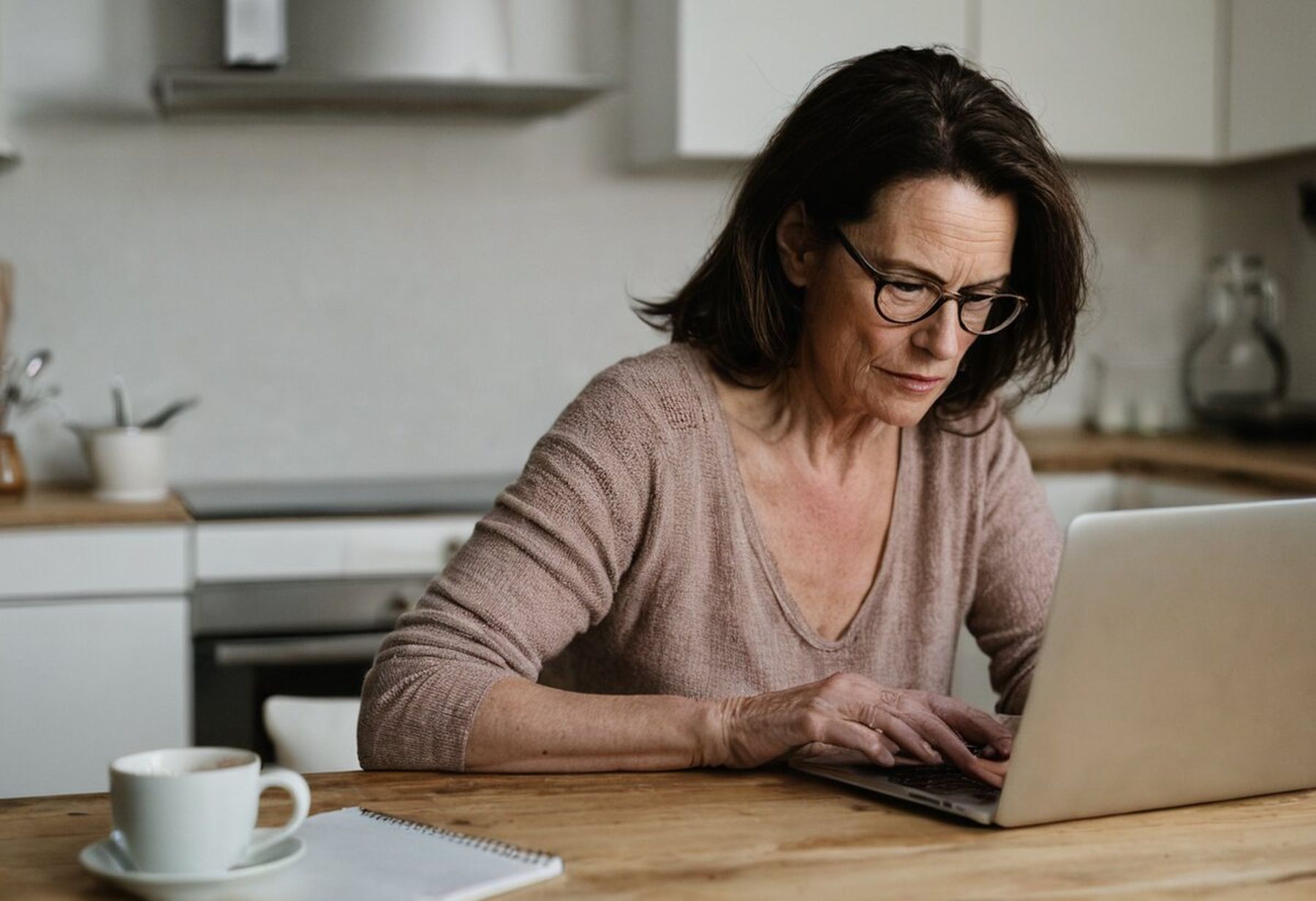 A student following a lesson on her laptop at the kitchen table